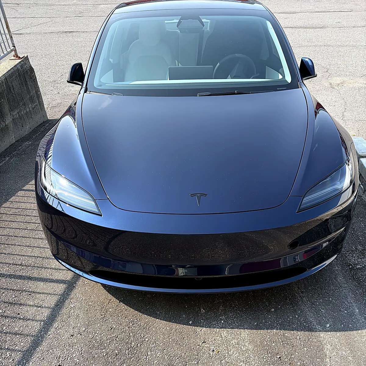 Vue avant d’une Tesla Model 3 bleu foncé avec une pellicule de protection fraîchement posée sur l’avant, devant le studio Wrap Senators à Ottawa