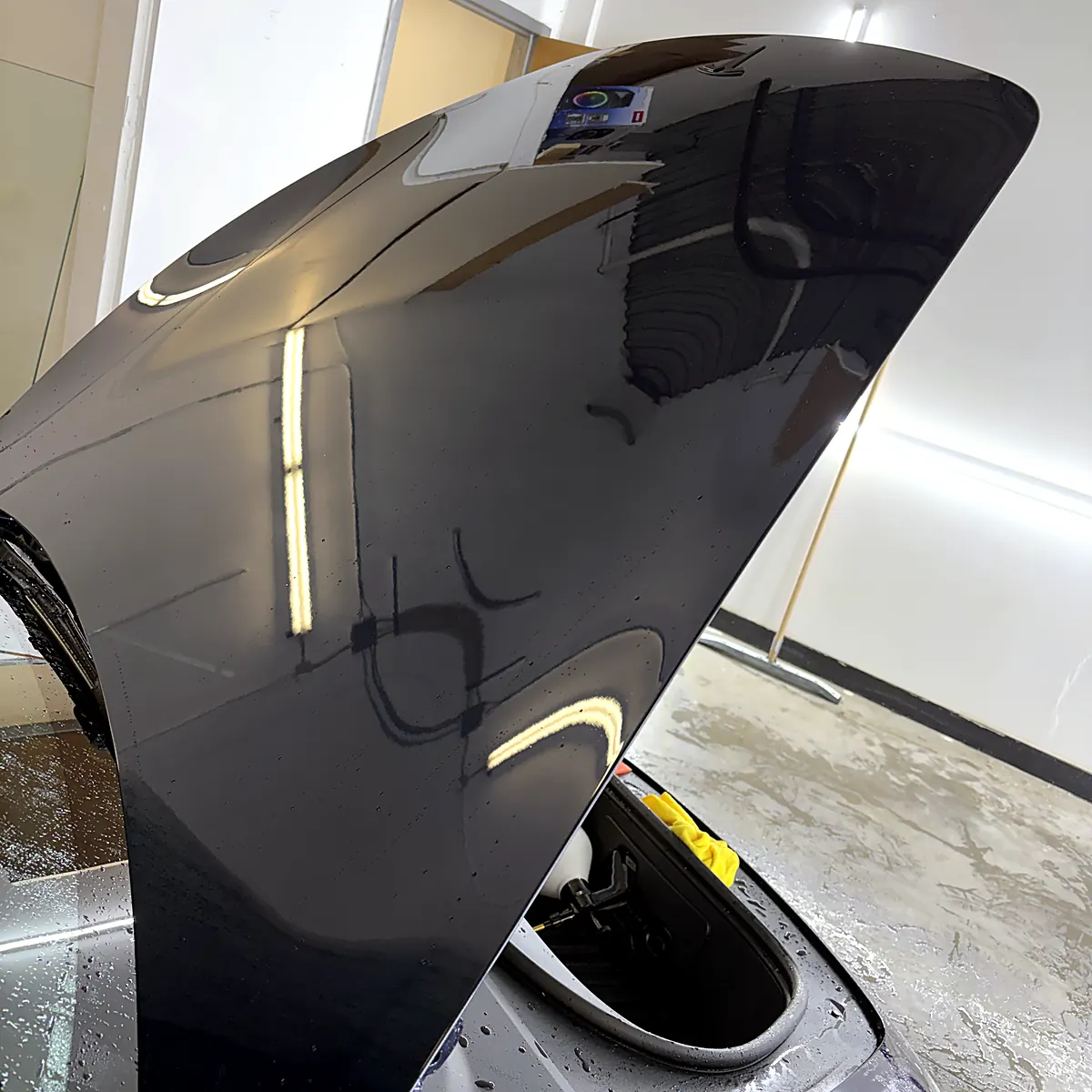 Capot relevé d’une Tesla Model 3, encore mouillé pendant la pose de la pellicule de protection au studio Wrap Senators à Ottawa