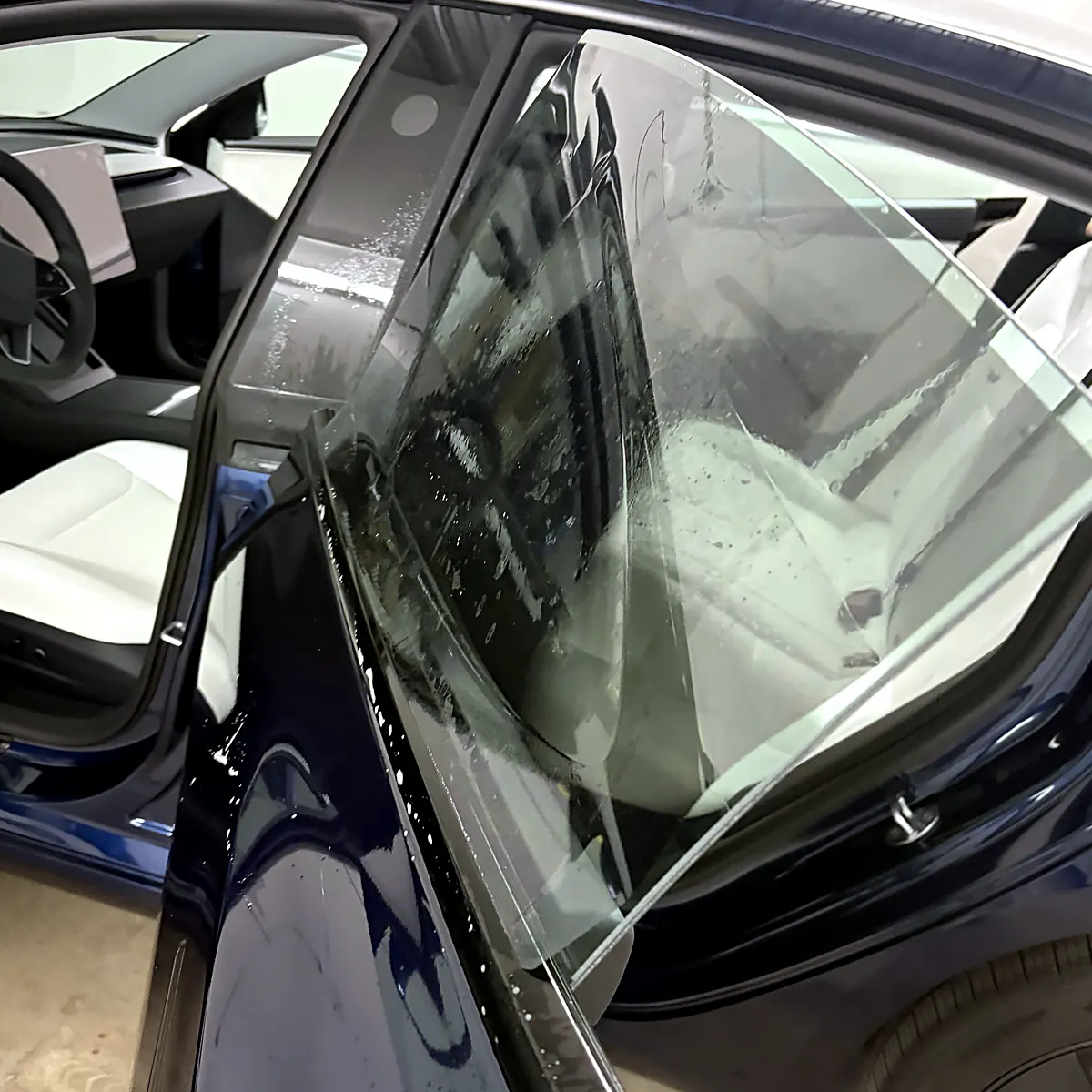 Pellicule de teinte fraîchement posée sur la vitre arrière d’une Tesla Model 3, encore mouillée, au studio Wrap Senators à Ottawa